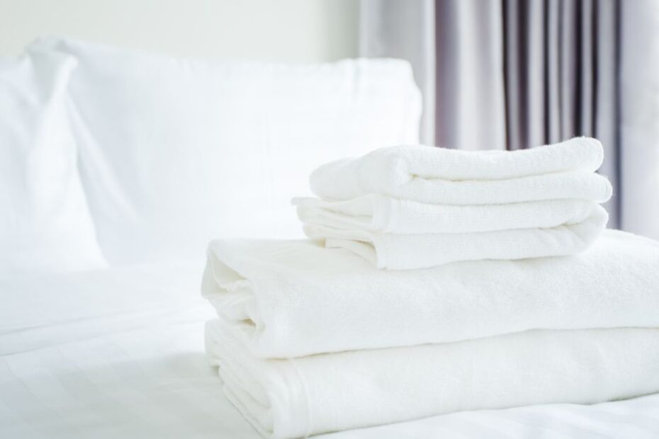 white towel on white bed in bed room