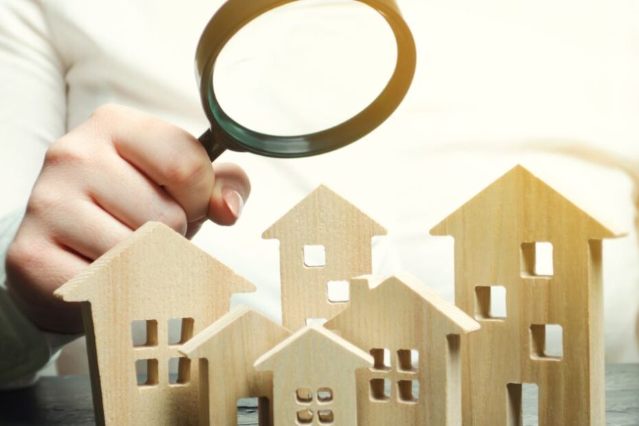 A woman is holding a magnifying glass over a wooden houses Real estate appraiser Property valuation appraisal Find a house Search for housing Real estate market analysis Selective focus