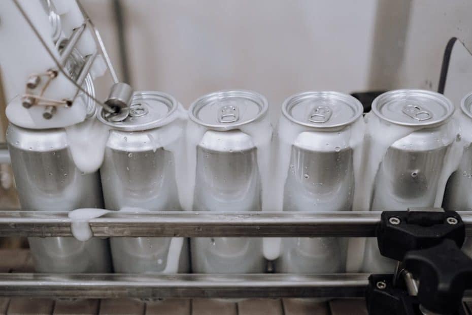 Close-up of aluminum cans on an assembly line in a modern brewery showing automation and machinery at work.