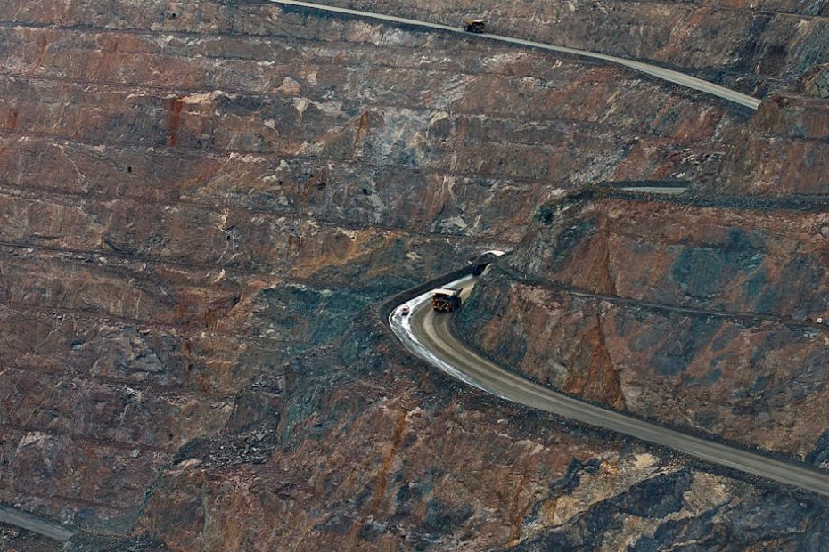 Aerial view of open-pit mine with haul trucks navigating winding roads.