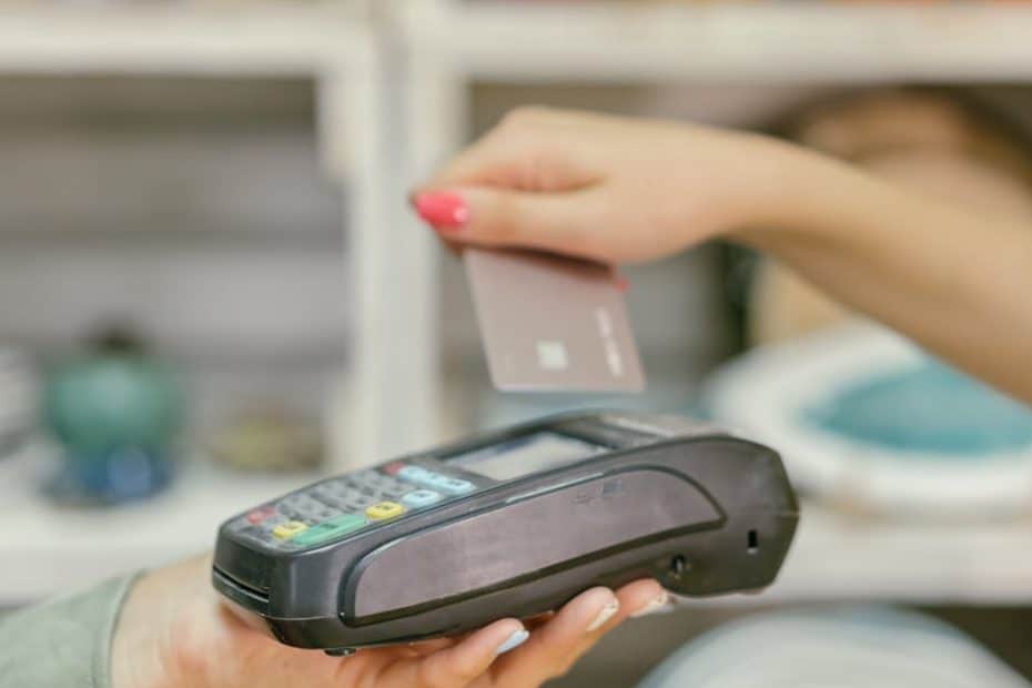 A hand using a credit card for payment at a point of sale terminal, close-up view.