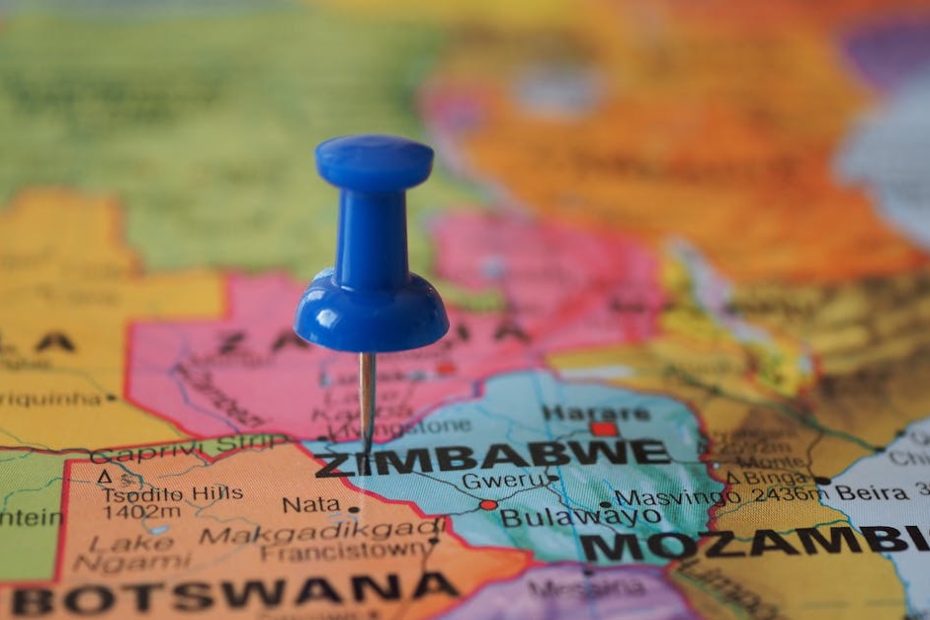A blue pushpin marks Zimbabwe on a colorful close-up map highlighting its geographical position.