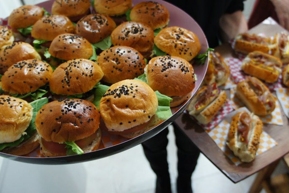 Close-up of trays with assorted mini burgers and hot dogs perfect for parties.