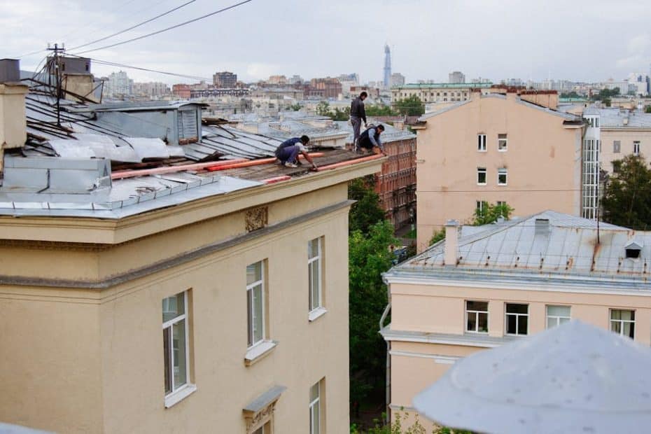 Construction workers repairing a rooftop in a vibrant cityscape.