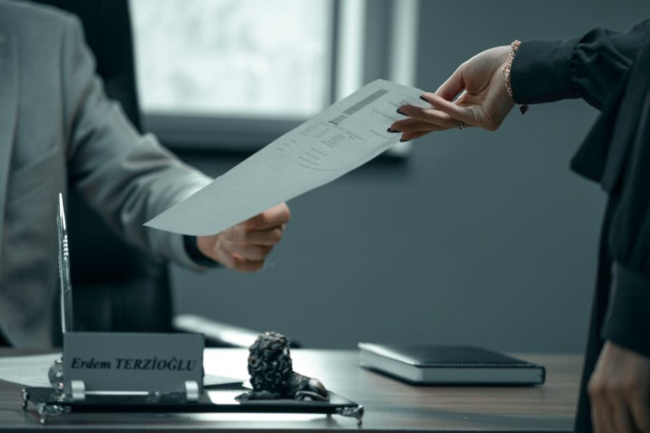 A formal business interaction with document exchange between professionals in a modern office setting.