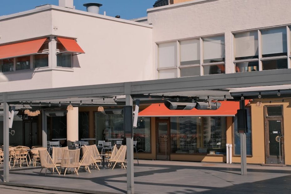 Sunny day at an outdoor cafe with modern architecture and empty seating area.
