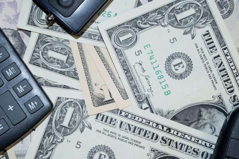 An arrangement of US dollar bills, car keys, and a calculator representing finance and investment concepts.