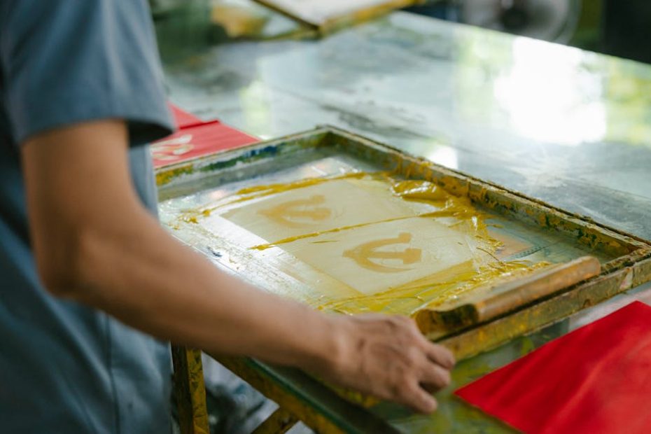 Artisan crafting screen prints indoors, showcasing creativity and skill in handmade art production.