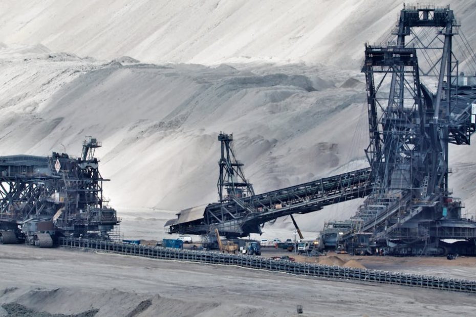 A large bucket wheel excavator operates in a vast industrial mining area, illustrating heavy machinery in action.