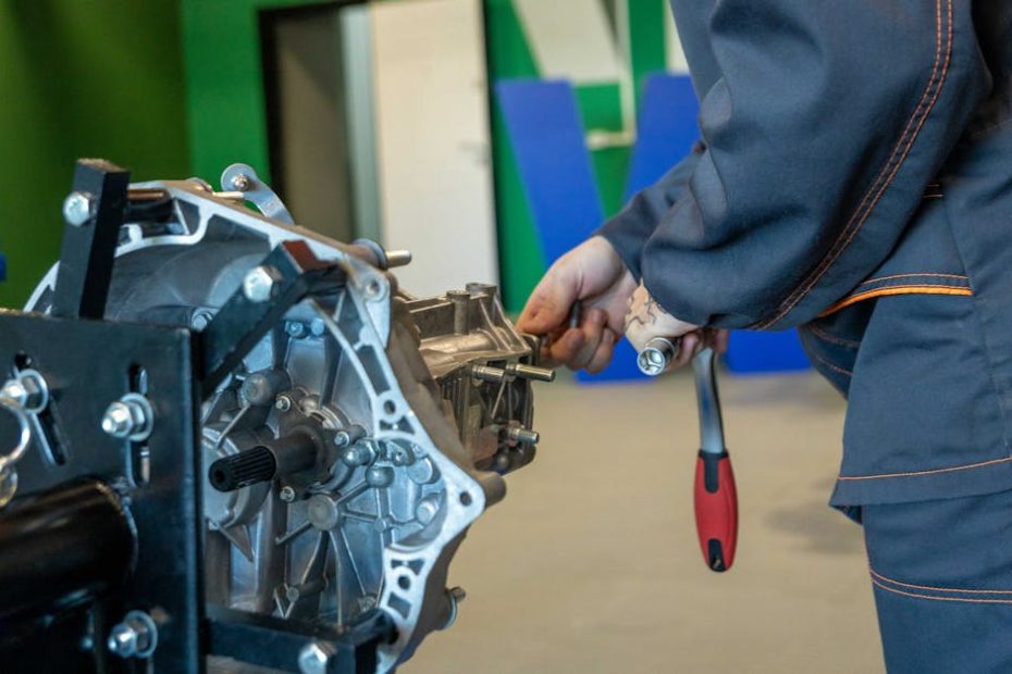 Mechanic uses tools to repair car transmission in an indoor workshop setting.