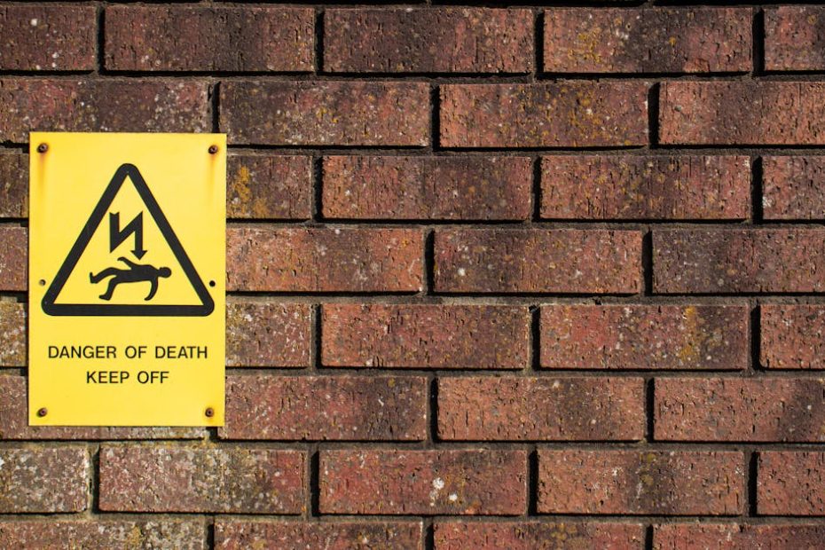 A bold warning sign on a brick wall displaying 'Danger of Death', emphasizing caution.