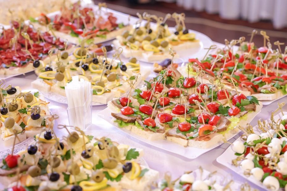 Vibrant display of assorted appetizers and finger foods at an indoor event buffet.
