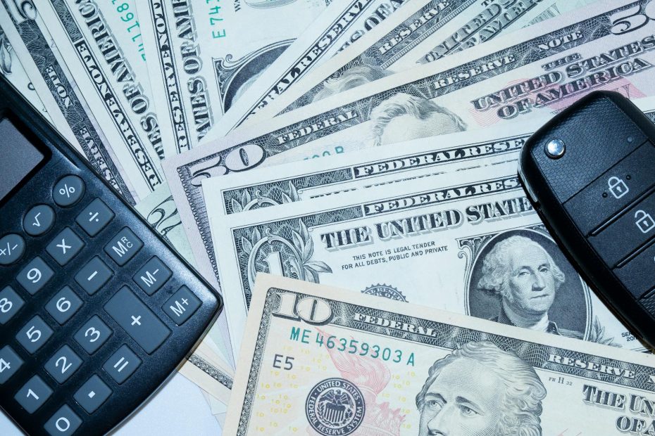 US dollars, calculator, and car keys representing vehicle finance