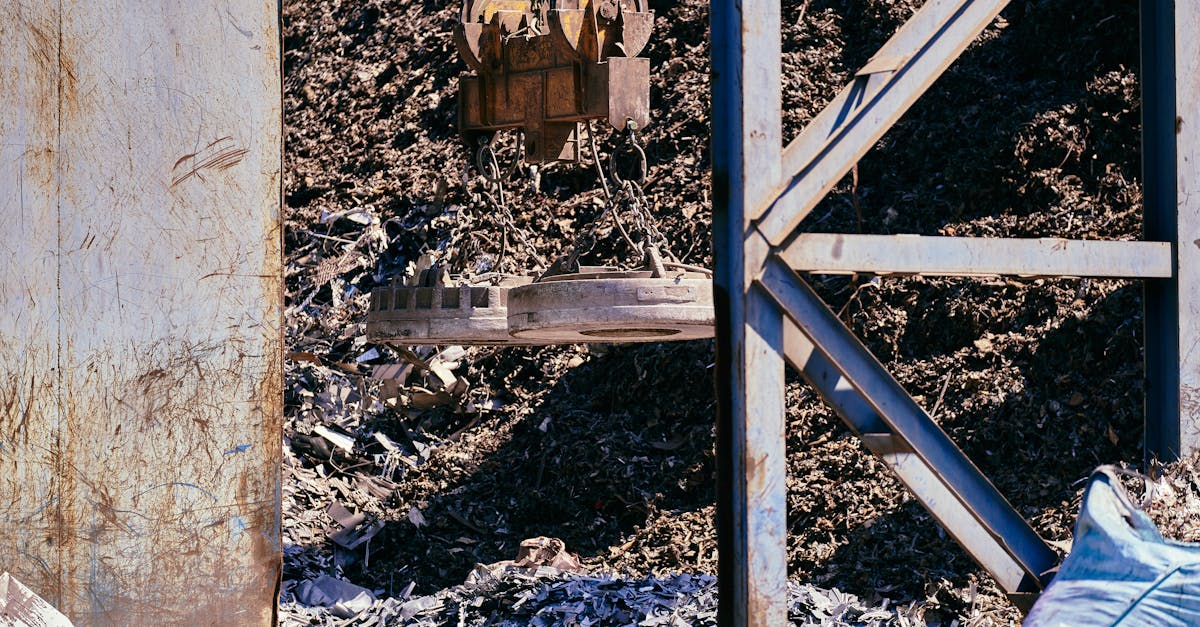 Magnetic crane sorting metal in an industrial scrapyard. Bright daylight highlights the steel and machinery.