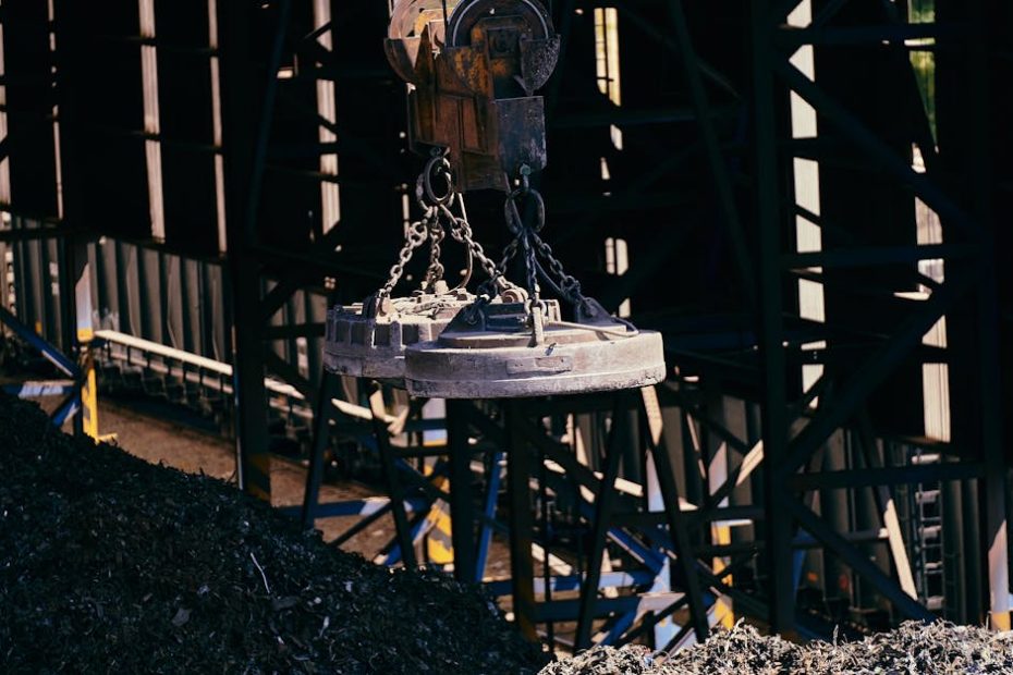Overhead view of industrial magnet lifting scrap metal in recycling plant.