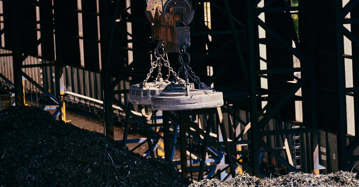 Overhead view of industrial magnet lifting scrap metal in recycling plant.