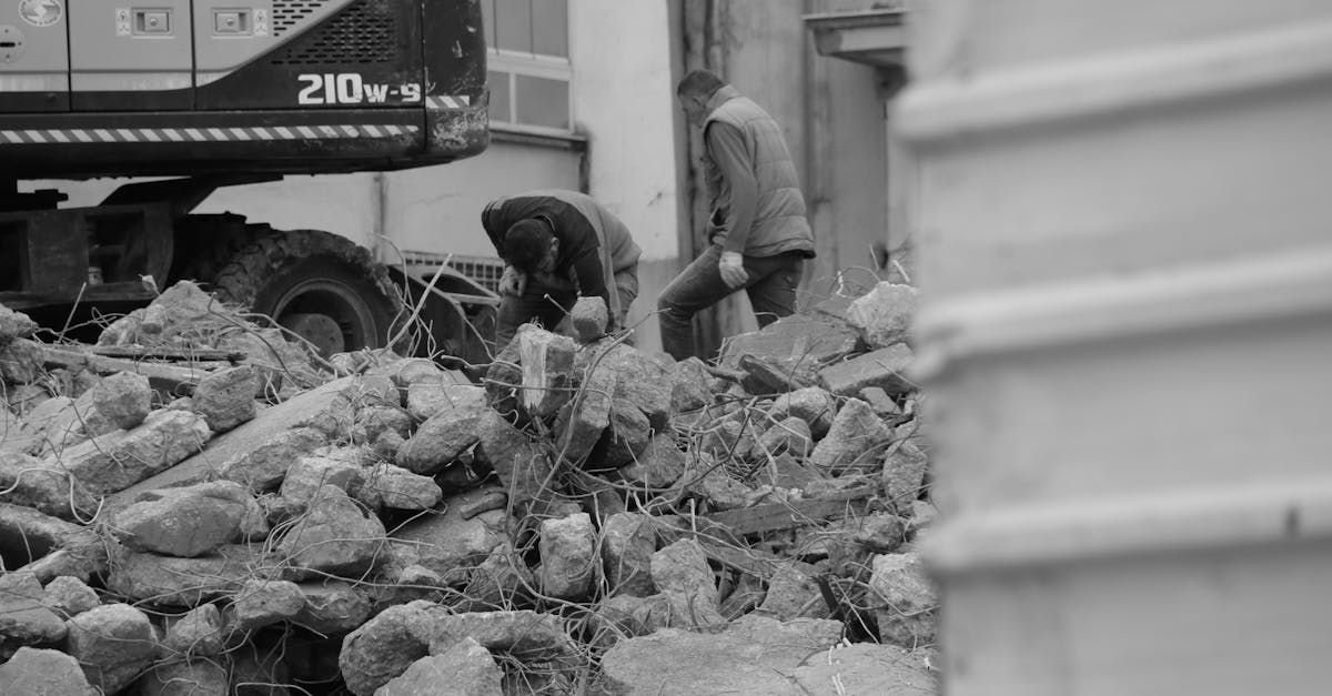 Black and white photo of workers and heavy machinery at a demolished construction site.