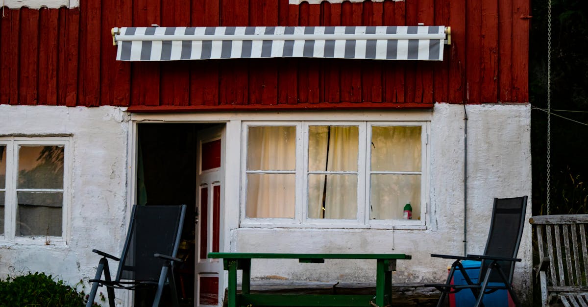 Charming rustic cabin with red and white facade and outdoor seating. Perfect for a cozy retreat.