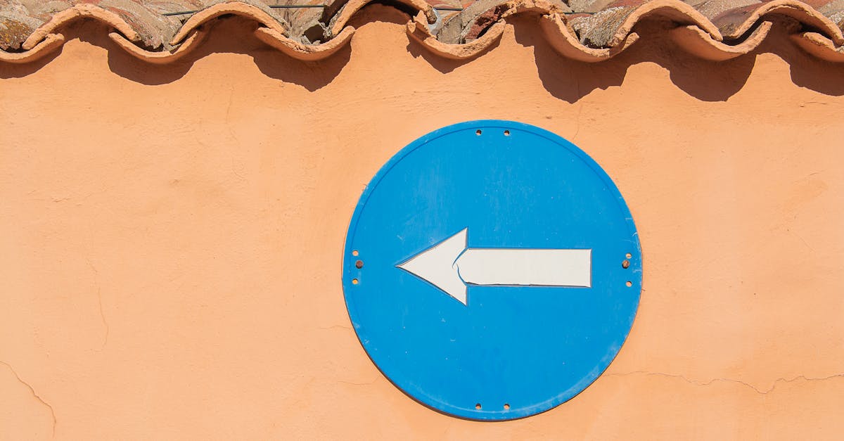 A blue left arrow traffic sign mounted on a terracotta tiled wall.