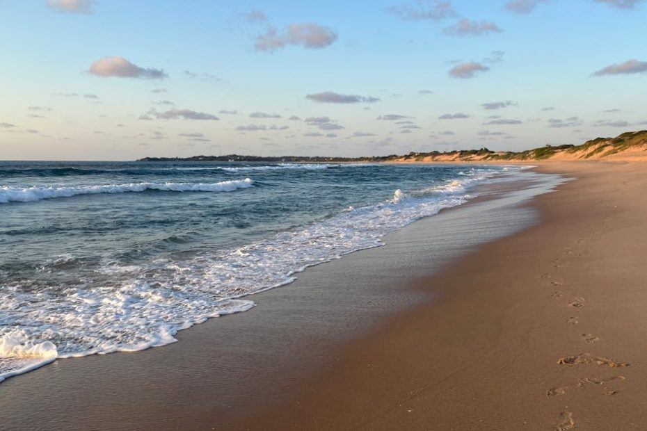 Serene sunset view of tranquil waves on Tofo Beach in Mozambique with soft golden sands.