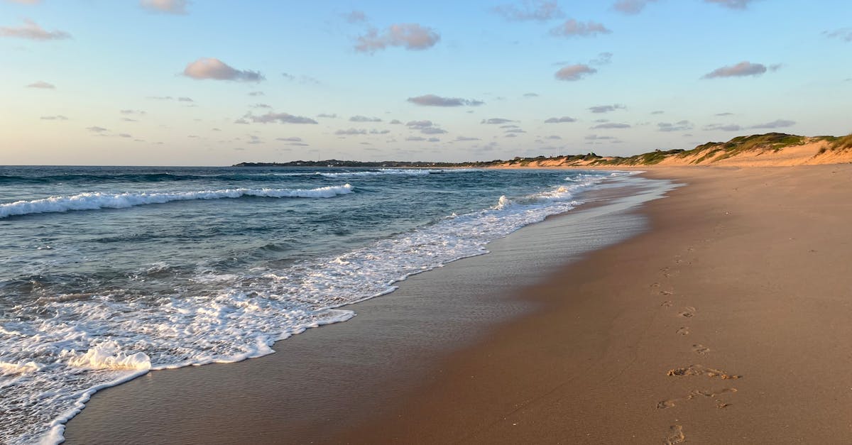 Serene sunset view of tranquil waves on Tofo Beach in Mozambique with soft golden sands.