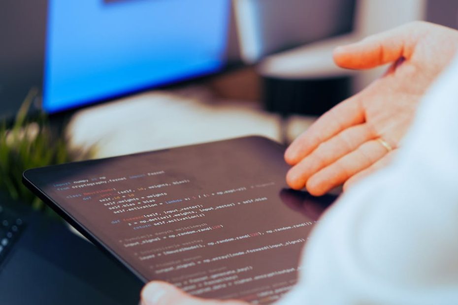 Software developer analyzing code on a tablet in a modern office workspace.