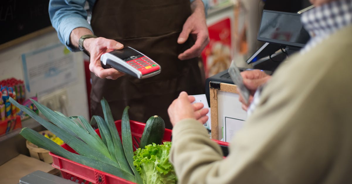 Close-up of customer paying for groceries with produce at a store checkout counter.