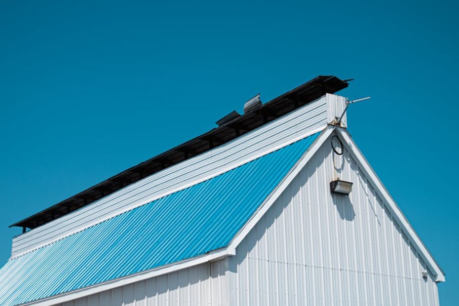 A white barn with a blue metal roof under a bright clear sky in Montreal.