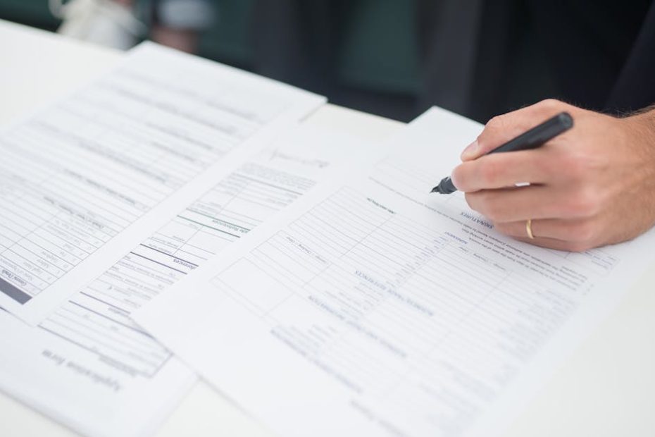 Close-up of a hand signing insurance documents in an office setting.